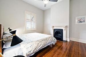 ein Schlafzimmer mit einem Bett und einem Kamin in der Unterkunft Azami - Charming Gilbert Cottage in Adelaide