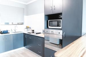 a kitchen with blue cabinets and a microwave at Michaels by the Sea in Yeppoon