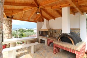 an outdoor kitchen with a brick fireplace and wooden ceiling at Vila Bilali in Ksamil