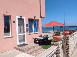 a pink house with a table and an umbrella at Apartments by the sea Tkon, Pasman - 21391 in Tkon