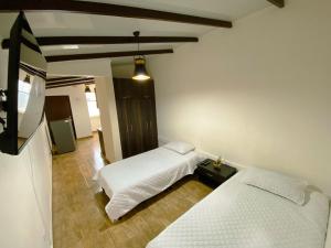 um quarto com duas camas e uma televisão em Los Ríos em Pereira