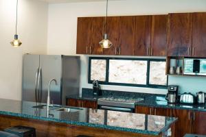 a kitchen with wooden cabinets and a counter top at Enclave Villa V3 -Overlooking Pitons & Ocean ! Wow in Soufrière