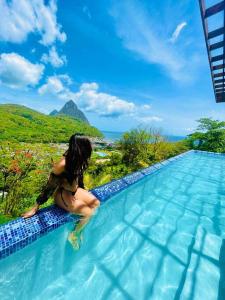 a woman sitting on the edge of a swimming pool at Enclave Villa V3 -Overlooking Pitons & Ocean ! Wow in Soufrière +45 photos