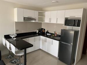 La cuisine est équipée de placards blancs et d'un réfrigérateur noir. dans l'établissement Apartamento JC Santa Cruz Norte, à Santa Cruz de la Sierra