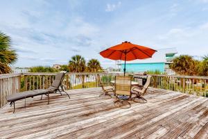 a patio with two chairs and an umbrella on a deck at Flood Reef Retreat - Blue Crab Cottage in Pensacola
