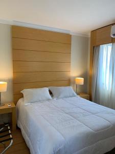 聖保羅的住宿－Hotel Aeroporto Congonhas，卧室配有一张白色大床和两盏灯。