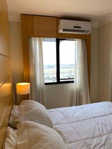 Hotel Aeroporto Congonhas في ساو باولو: غرفة نوم بسرير ابيض ونافذة