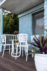 een patio met witte stoelen en een tafel op een veranda bij Michaels by the Sea in Yeppoon