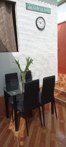 a table with four chairs and a clock on a wall at POSADA MIS 3 BENDICIONES in Paracas