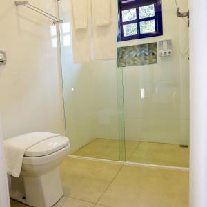 a bathroom with a toilet and a glass shower at Pequeno Paraíso in Foz do Iguaçu