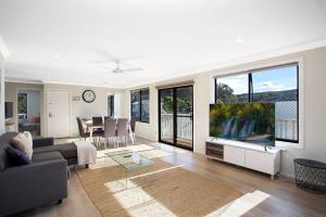 a living room with a couch and a flat screen tv at Renovated Coastal getaway with water views in Umina