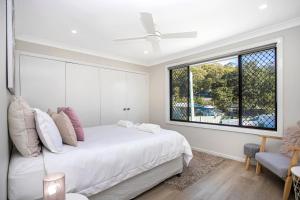 a bedroom with a white bed and a window at Renovated Coastal getaway with water views in Umina +10 photos