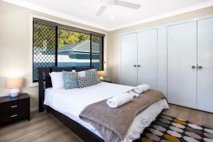 a bedroom with a bed and a large window at Renovated Coastal getaway with water views in Umina