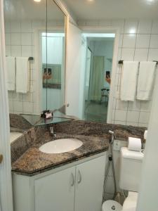 uma casa de banho com um lavatório, um espelho e um WC. em Lindo Flat Beira Mar 401 em Fortaleza