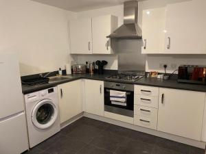 y cocina con fogones y lavadora. en Comfy 2-bed home - Contractors and Leisure en West Bromwich