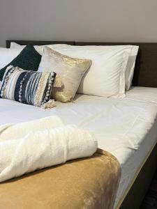 ein weißes Bett mit Kissen darauf in der Unterkunft Comfy 2-bed home - Contractors and Leisure in West Bromwich