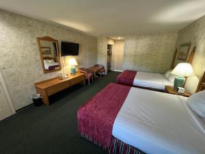 a hotel room with two beds and a desk at Colonel Williams Resort and Suites in Lake George