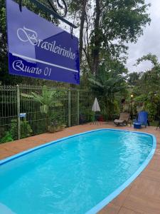 a blue swimming pool with a sign in front of a fence at Pequeno Paraíso in Foz do Iguaçu