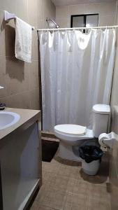 a bathroom with a toilet and a white shower curtain at Casa la Conchita in San Luis Potosí