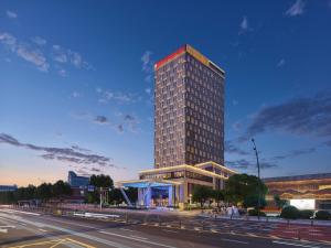 un grand bâtiment avec un panneau rouge en haut dans l'établissement Hilton Garden Inn Jiaxing Xiuzhou, à Jiaxing