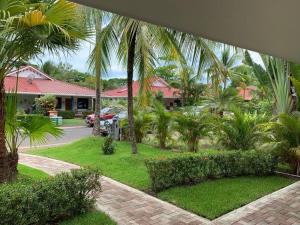 a view of a resort with palm trees and a driveway at Golf Beach House w/ Pool (5 min. walk to beach!) in Tambor