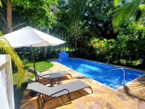 uma piscina com duas cadeiras e um guarda-sol em Golf Beach House w/ Pool (5 min. walk to beach!) em Tambor