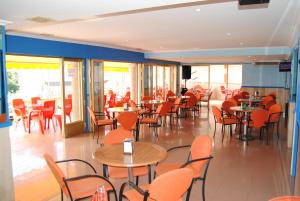 a restaurant with orange chairs and tables and tables and windows at Hotel Riveiro in Sanxenxo +26 photos