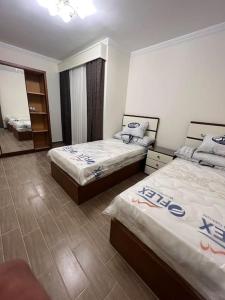 1 dormitorio con 2 camas y espejo en شاليه ارضى على حمام سباحه, en Qaryat Shākūsh