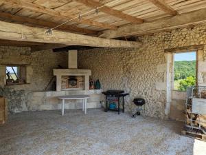 um quarto com paredes de pedra, uma mesa e uma lareira em Gîte Montignac-le-Coq, 3 pièces, 6 personnes - FR-1-653-4 em Montignac-le-Coq