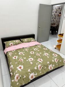 a bedroom with a bed with a green and pink blanket at Aisy Guest House - MUSLlM Only in Kangar