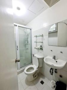 een witte badkamer met een toilet en een wastafel bij Modern & Spacious 2BR Condo with Netflix & Pool Acess in San Juan Manila in Manilla