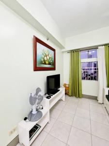a living room with a flat screen tv on a white floor at Modern & Spacious 2BR Condo with Netflix & Pool Acess in San Juan Manila in Manila