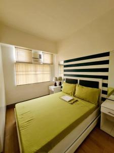 een slaapkamer met een groot geel bed met een laptop erop bij Modern & Spacious 2BR Condo with Netflix & Pool Acess in San Juan Manila in Manilla