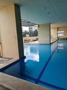a swimming pool with blue water in a building at Modern & Spacious 2BR Condo with Netflix & Pool Acess in San Juan Manila in Manila