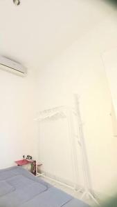 Cama blanca en habitación con pared blanca en Townhouse MisNov good escape from Jakarta, 