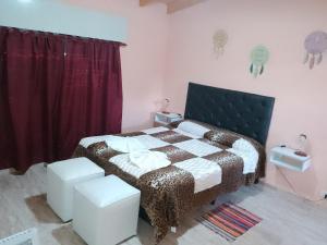 1 dormitorio con 1 cama y 2 taburetes en Mí cielo en Huerta Grande