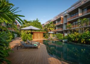 a swimming pool with chairs and an umbrella next to a building at Angkor Grace Residence & Wellness Resort in Siem Reap
