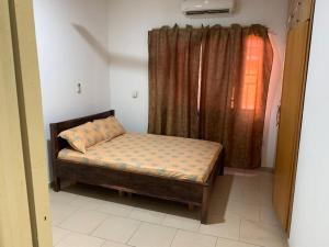 ein kleines Bett in einem Zimmer mit Fenster in der Unterkunft 2 Bedroom @ Devtraco Estates -Tema Comm 25 in Tema