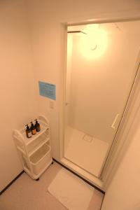 a bathroom with a walk in shower next to a refrigerator at 遊悠館 in Chitose