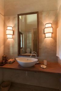 a bathroom with a sink with a mirror and lights at Tiger Tops Karnali Lodge in Bardia