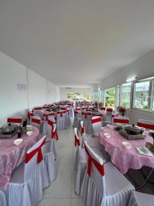Cette grande chambre comprend des tables et des chaises avec des archets rouges. dans l'établissement NAM DU PALACE Hotel, à Nam Du
