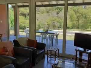 a living room with a television and a table with chairs at Casa de Campo con Bosque y Pileta in Tandil