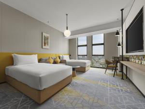 una camera d'albergo con letto e divano di Hilton Garden Inn Jiaxing Xiuzhou a Jiaxing