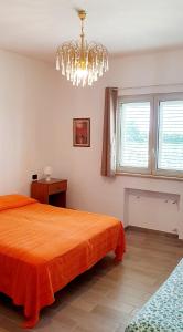 1 dormitorio con cama de color naranja y lámpara de araña en Agape casa vacanze, en Giardini Naxos