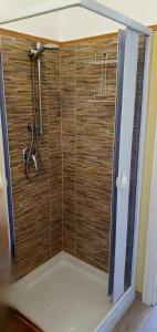 y baño con ducha y pared de madera. en Agape casa vacanze en Giardini Naxos
