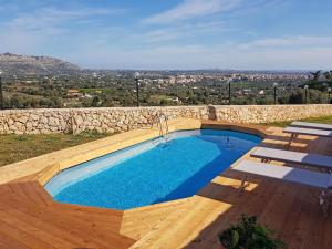 a swimming pool with a wooden deck and a stone wall at Holiday Home Floridia with Private Pool in Floridia +14 photos