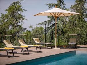 une terrasse avec des chaises et un parasol ainsi qu'une piscine dans l'établissement Belvilla by OYO Villa il Castello, à Castiglion Fiorentino