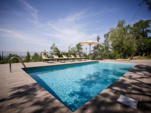 - une piscine avec des chaises et un parasol dans l'établissement Belvilla by OYO Villa il Castello, à Castiglion Fiorentino