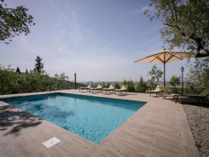 - une piscine avec des chaises et un parasol dans l'établissement Belvilla by OYO Villa il Castello, à Castiglion Fiorentino