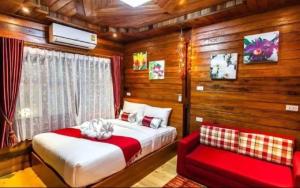 1 dormitorio con 1 cama y 1 sofá rojo en Areeya phubeach resort wooden house, en Ban Chong Phli